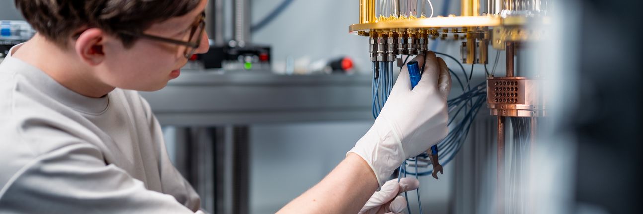 A scientist assembles cables on an open cryostat for superconducting quantum computing.